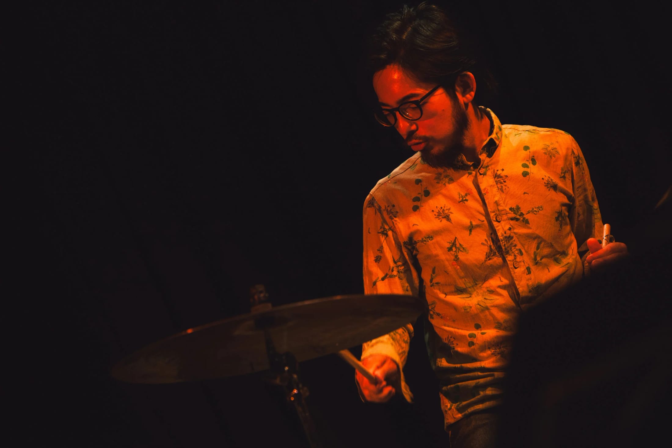 Hironori Momoi behind the drum kit under warm stage light.